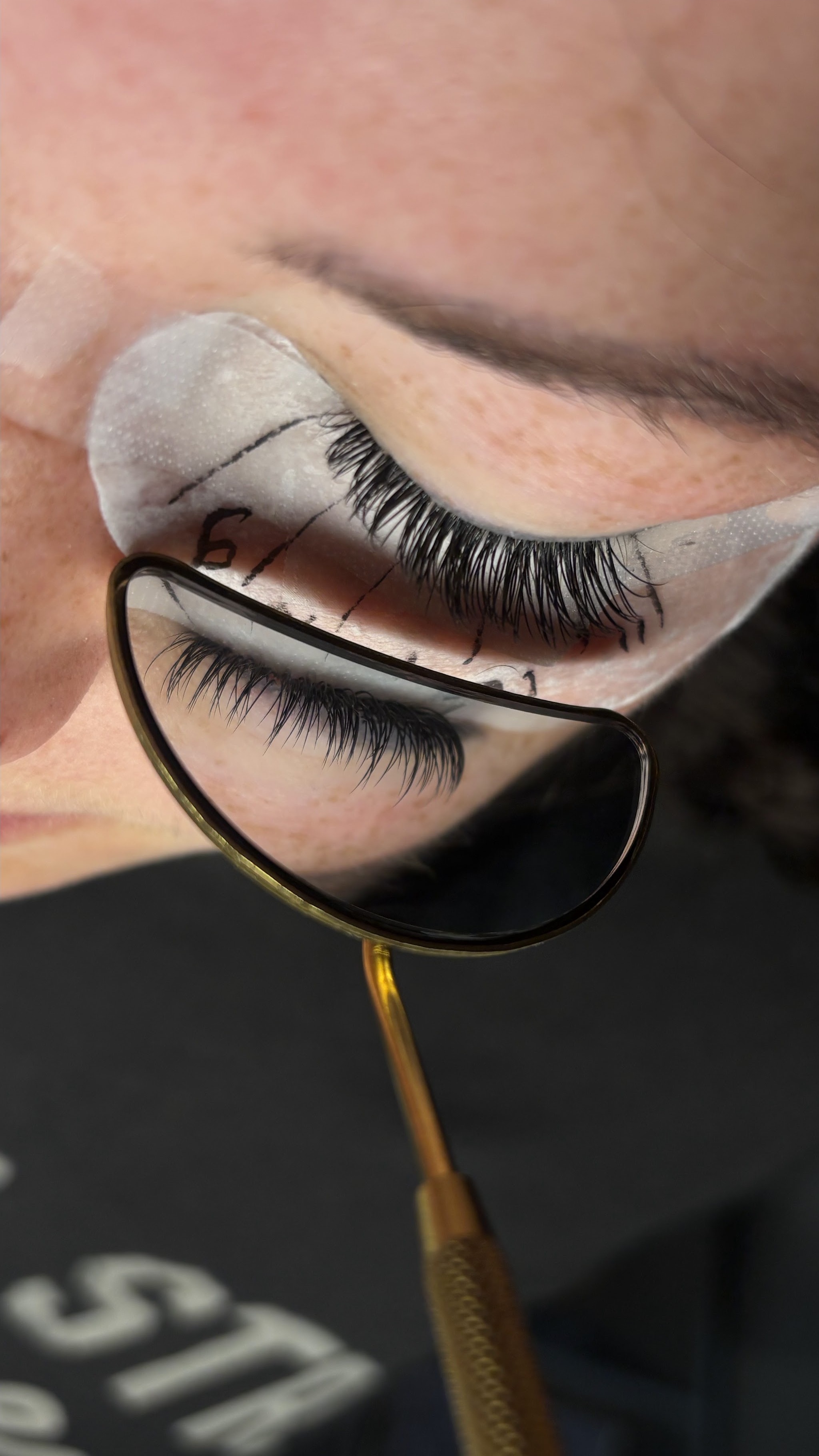 Lash extensions worden gezet, met een gouden spiegeltje dat de nieuwe set laat zien