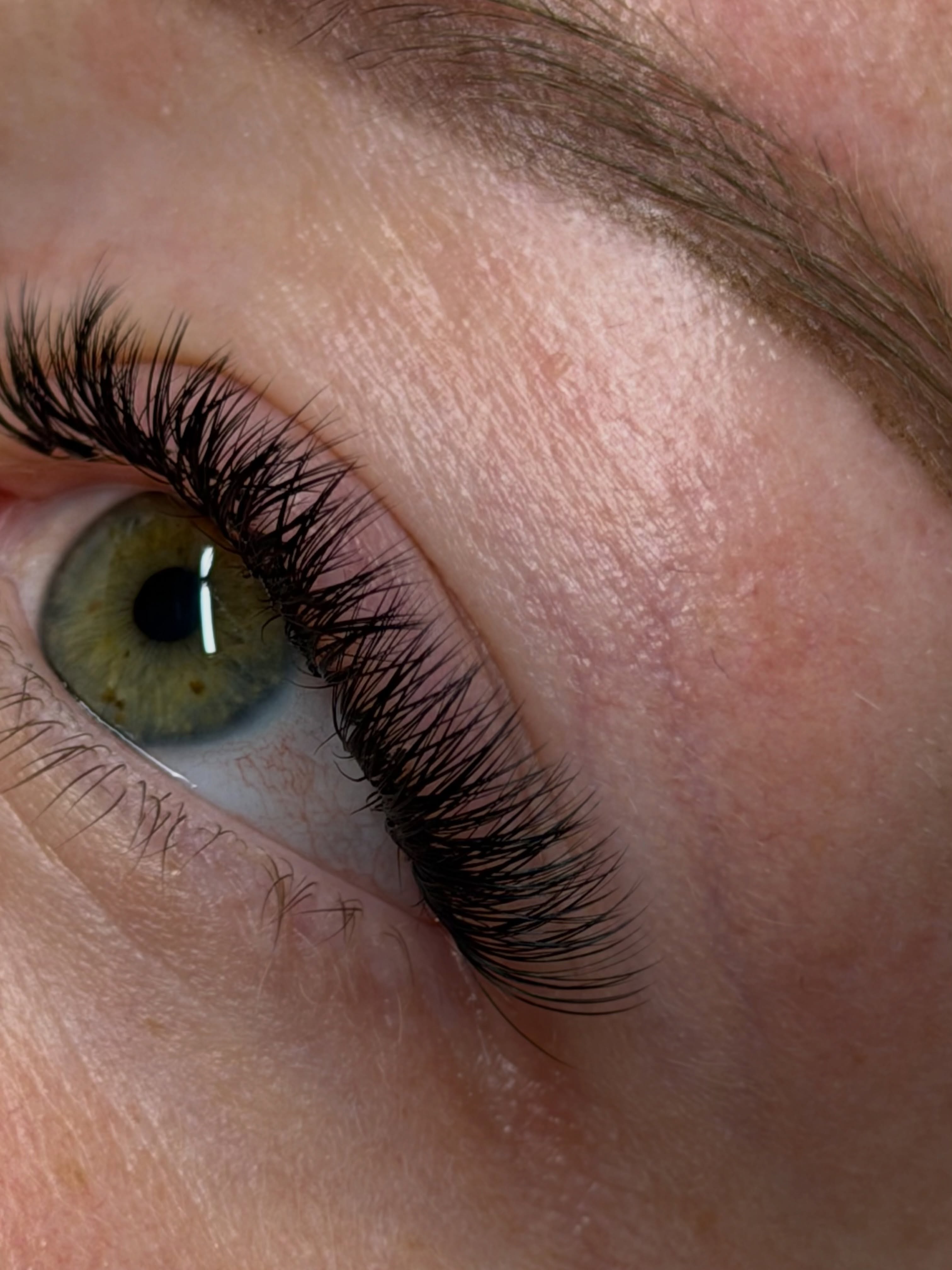Macro-opname van een groen oog met een volle set lash extensions